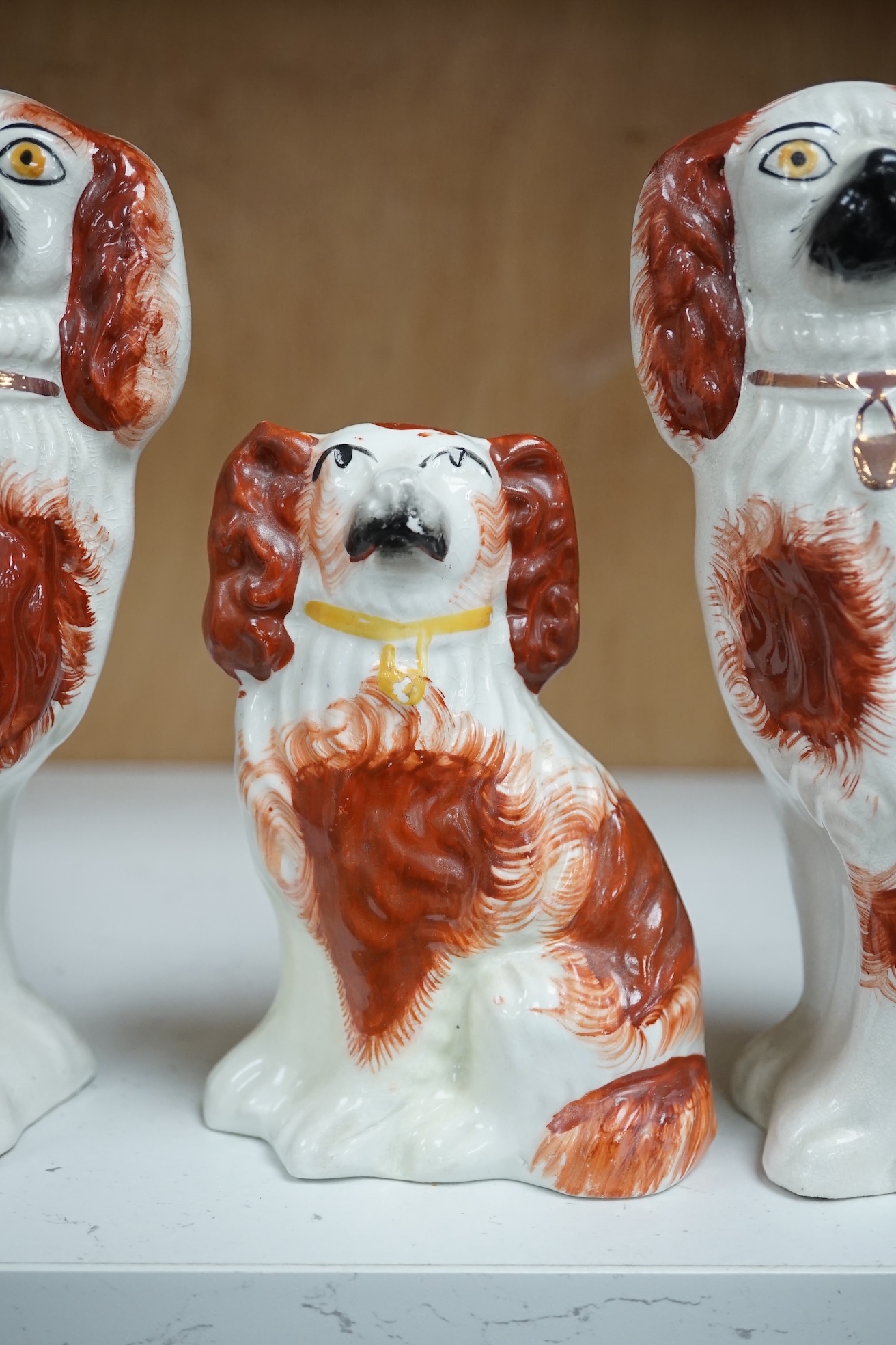 A pair of Staffordshire potter spaniels, and a similar smaller example, taller 18cm. Condition - smaller and one larger heavily restored